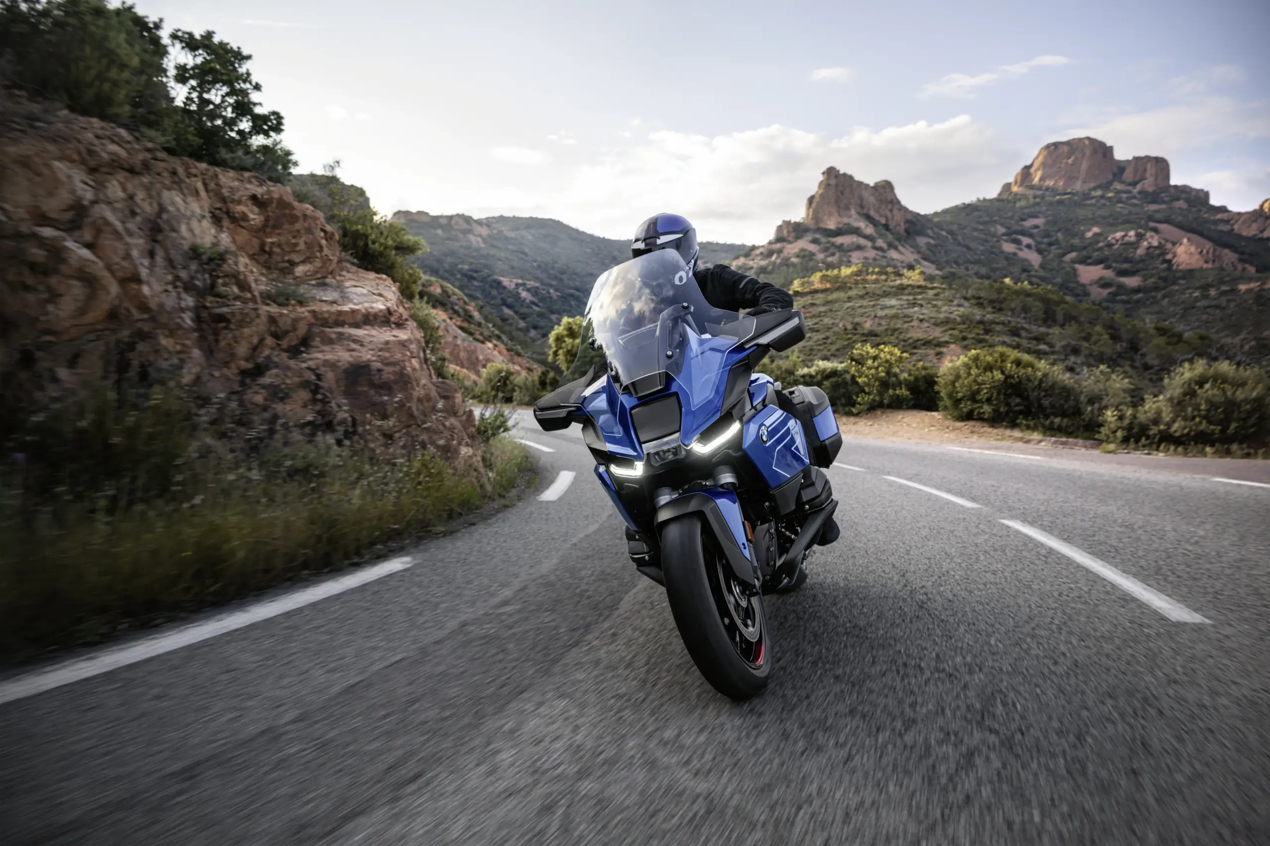 BMW R 1300 RT coming through a mountain road with dramatic scenery and motion blur
