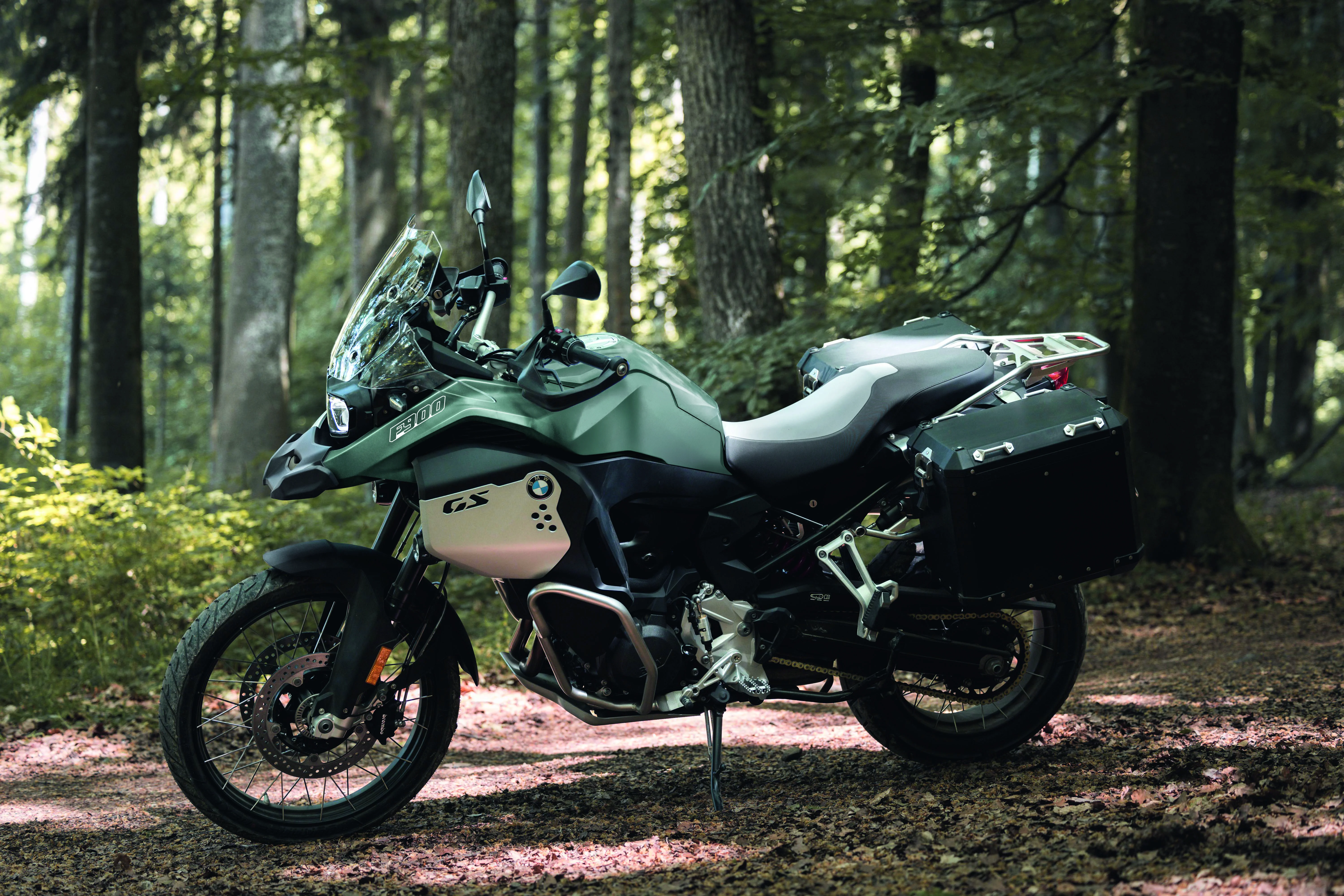2026 BMW F 900 GS Adventure parked in a forest clearing with filtered daylight behind it.